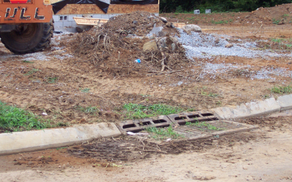 Photo of piles of dirt at construction site and a storm drain clogged with dirt and construction trash